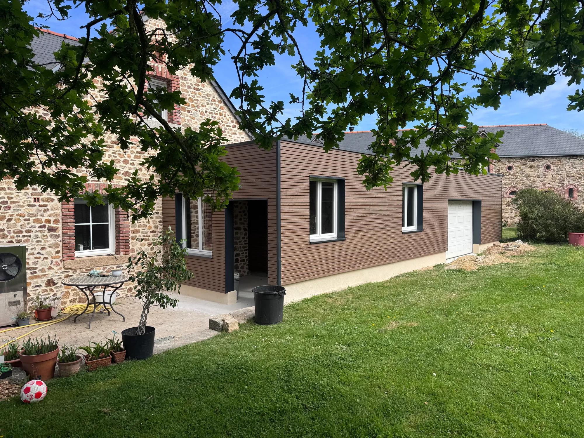 Extension à ossature bois et toit plat accolée à une maison en pierre