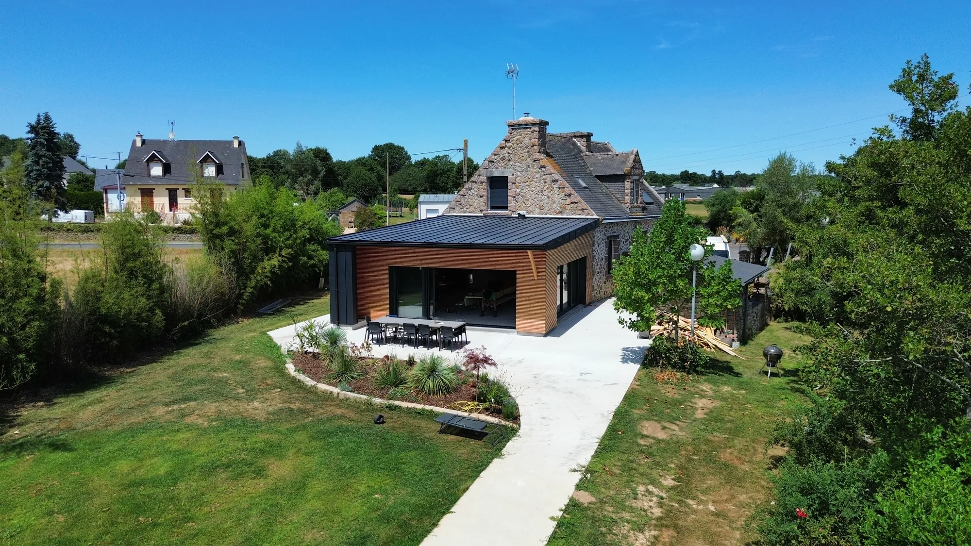 Vue par drone d'une extension bois à toiture anthracite sur une maison en pierre